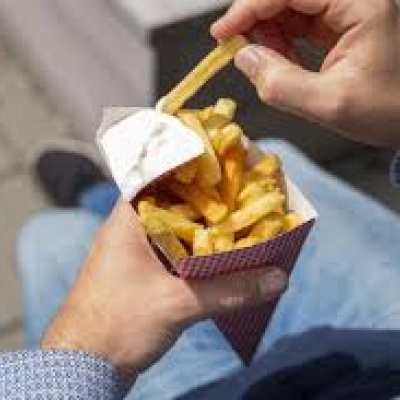 Handen die een puntzak friet met mayonaise vasthouden