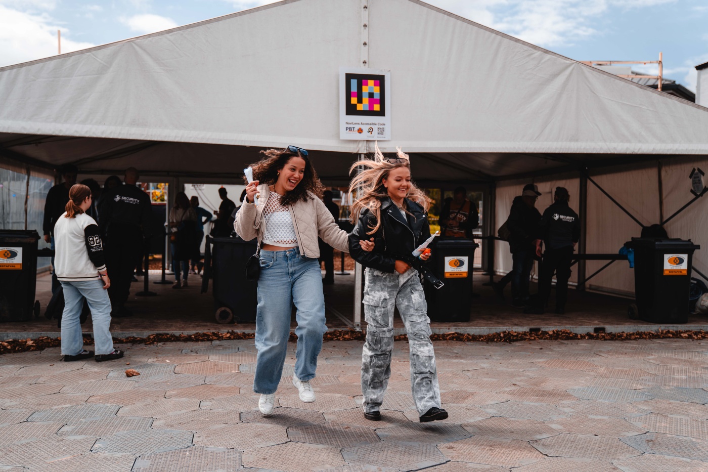 Two visitors have just entered the festival with a NaviLens sign behind them on a tent